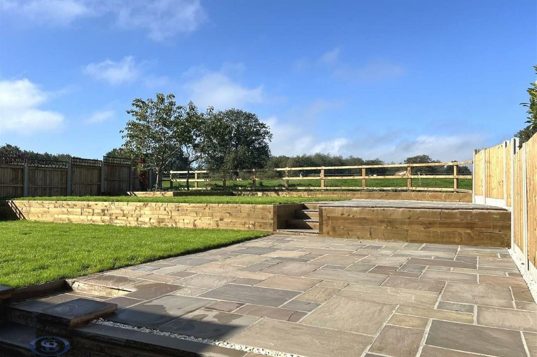 Landscaped terraced garden with patio and field views