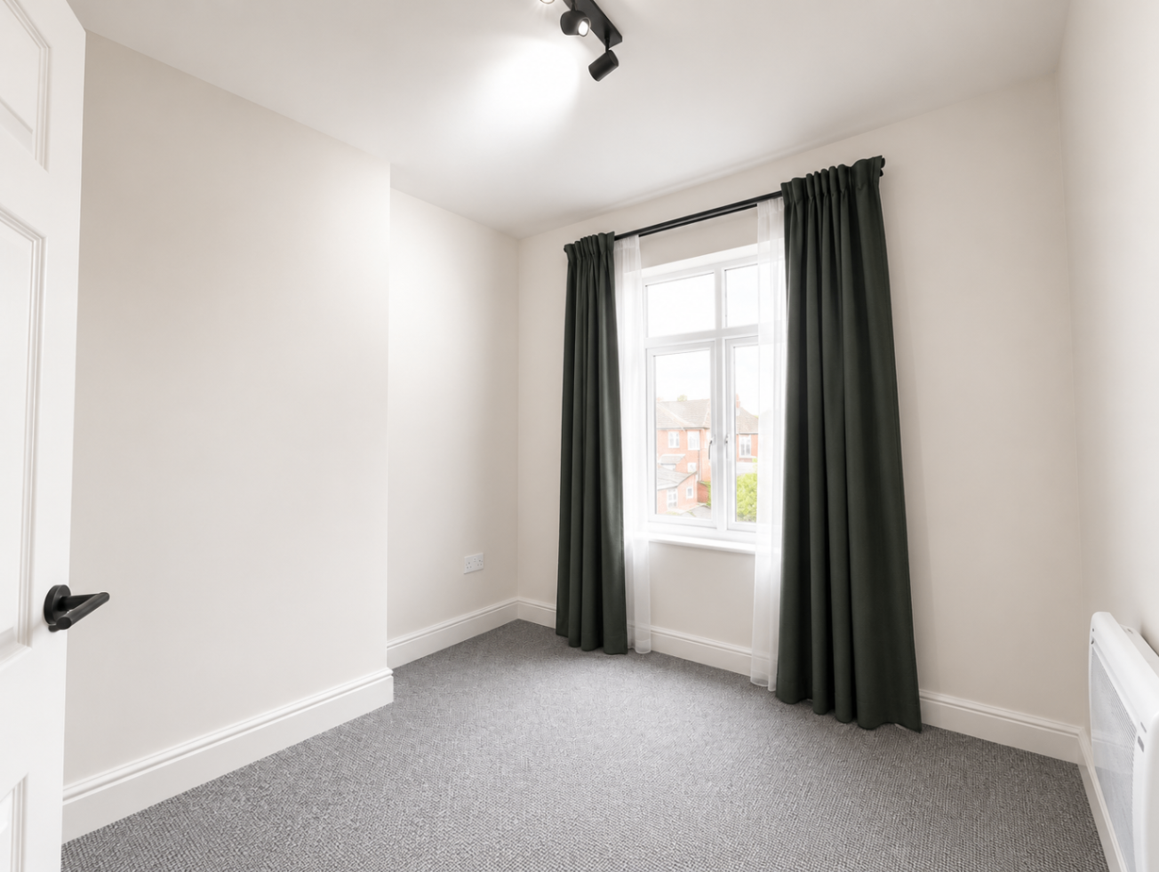 Bedroom with tall window, grey carpet and green curtains