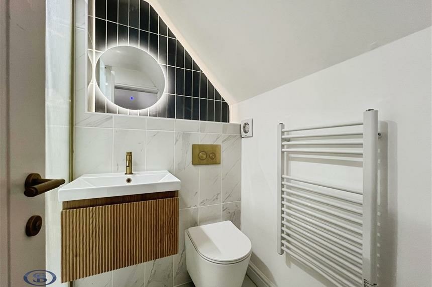 En suite with fluted vanity and backlit mirror