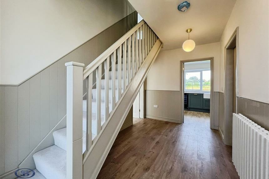 Hallway with panelled staircase and oak flooring