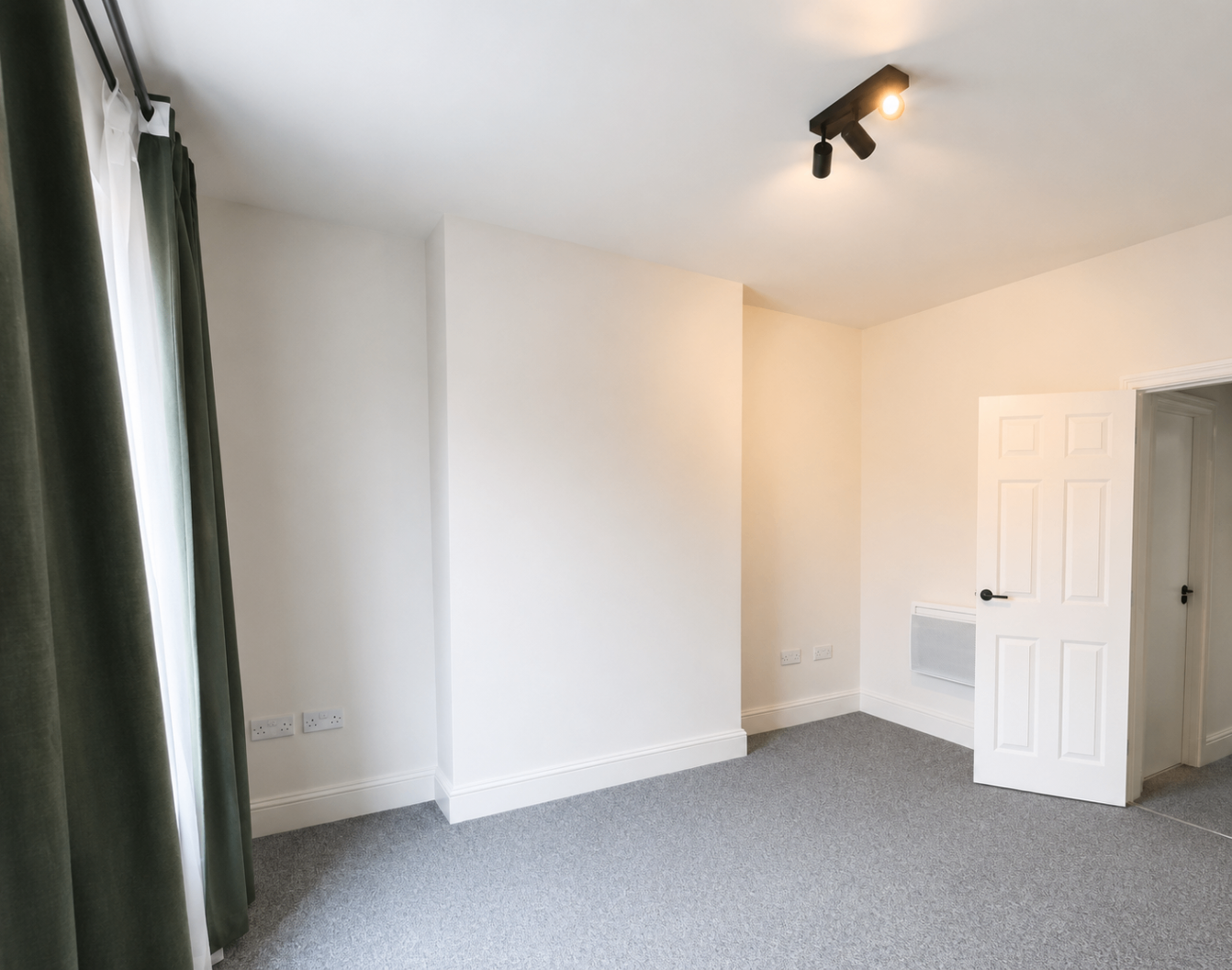 Light-filled bedroom with soft grey carpet and black ceiling track lights